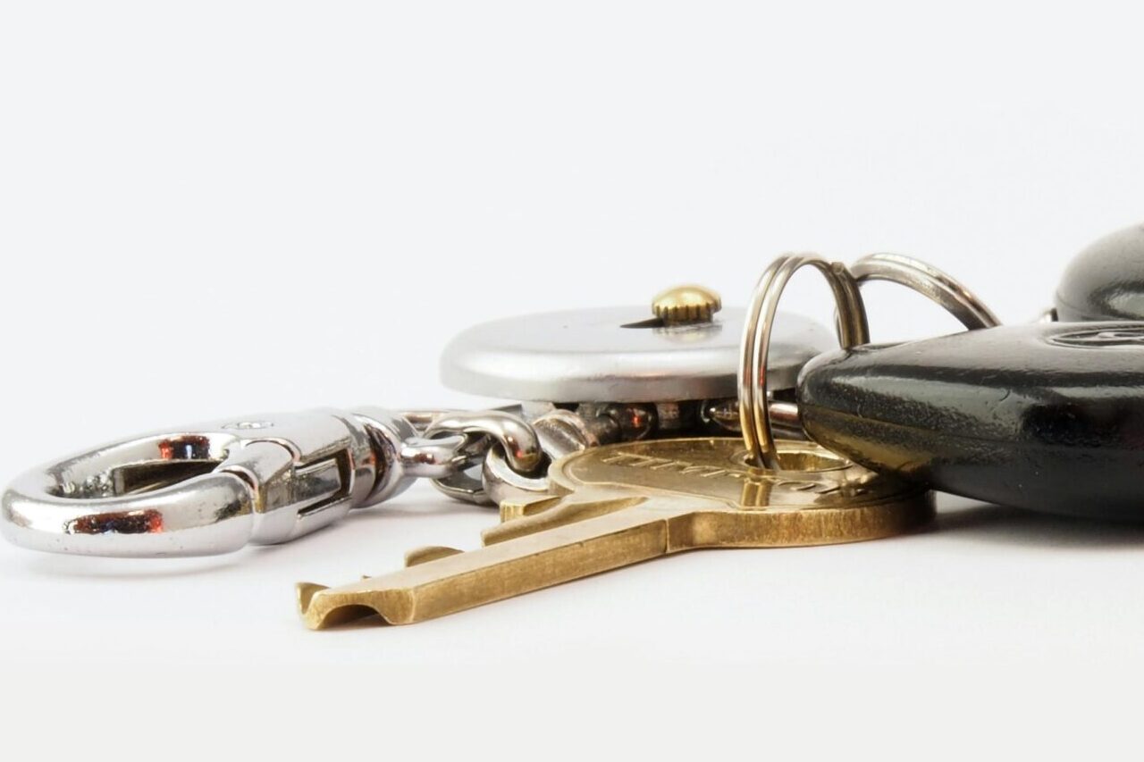 Detailed image of car keys on a white surface, including a key fob and keychain.