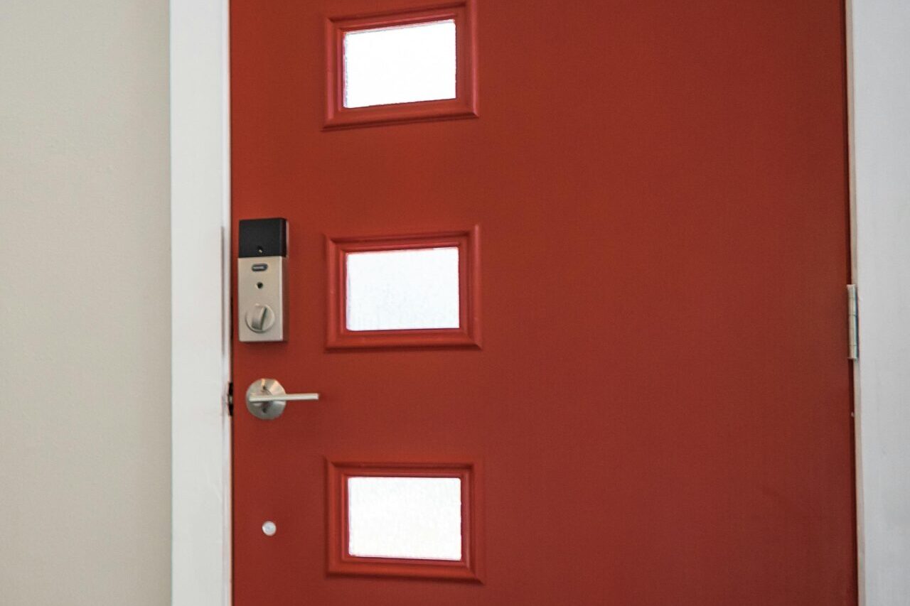 Contemporary interior with a vibrant red entrance door and stairs, showcasing minimalist design.