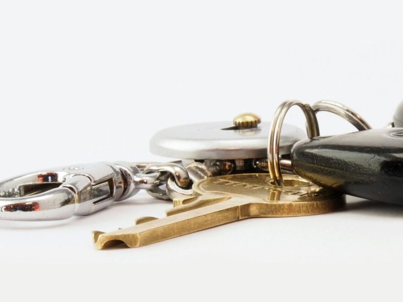 Detailed image of car keys on a white surface, including a key fob and keychain.