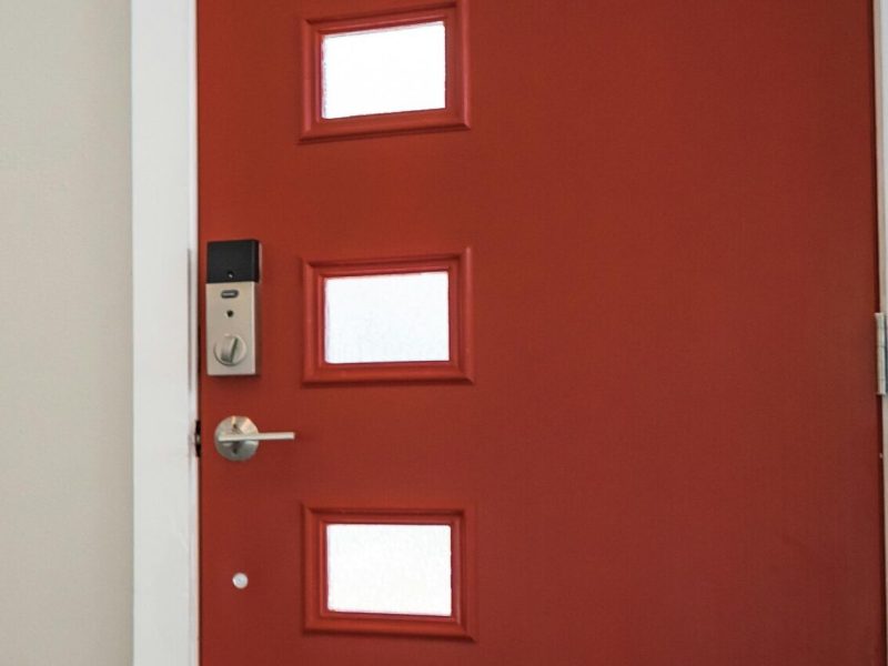 Contemporary interior with a vibrant red entrance door and stairs, showcasing minimalist design.